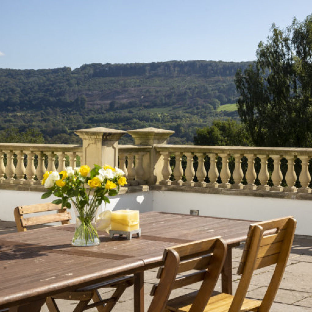 Terrance View from Woodbank House with Wooden Patio Furniture and Yellow and White Flowers
