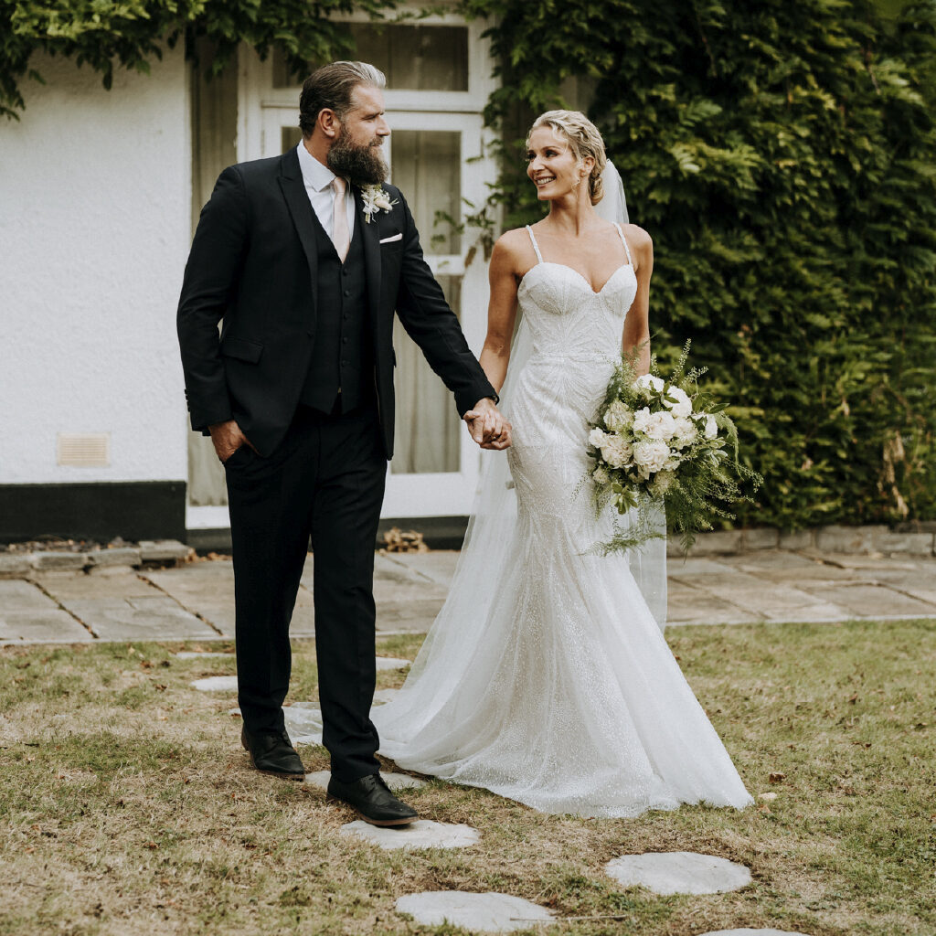 Bride and groom walking hand in hand on circular stone path