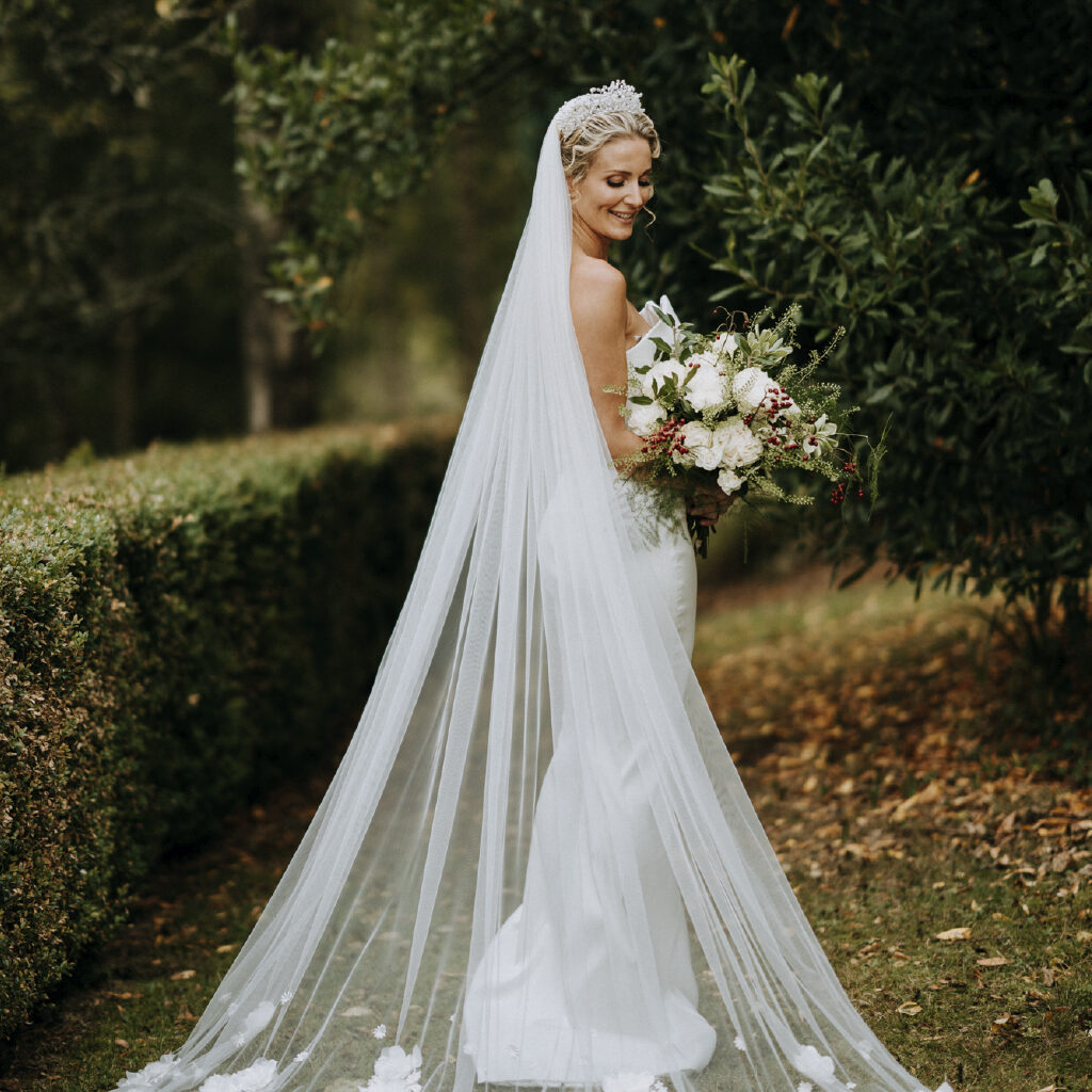 Bride in the autumnal grounds of Woodbank house displaying her veil looking down to the ground