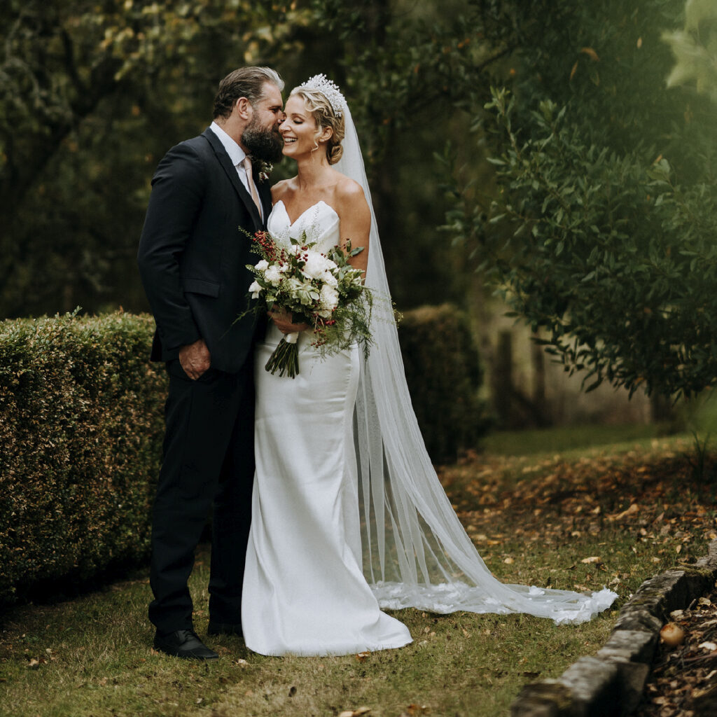 Groom whispering to his bride in the autumnal grounds of Woodbank house