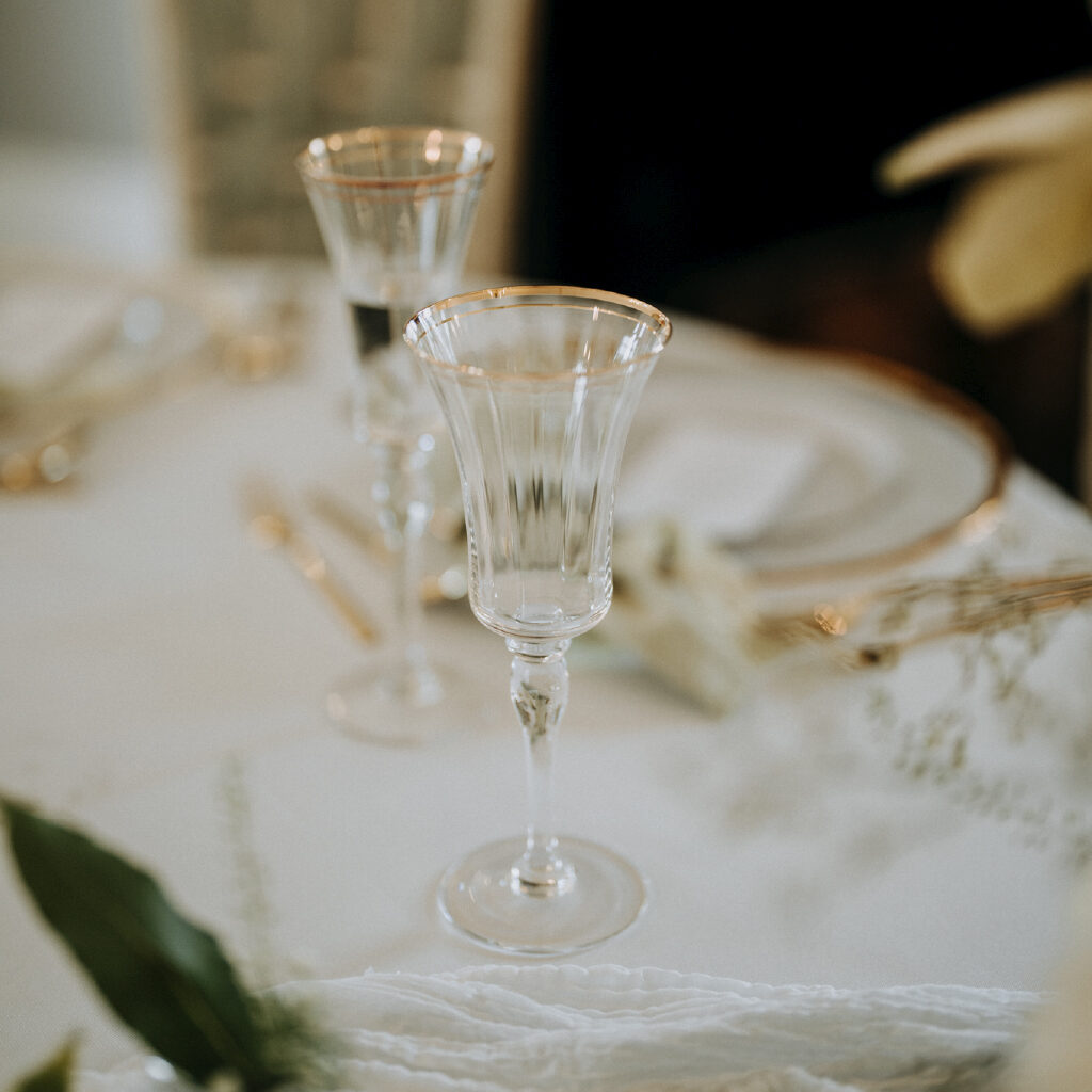 Close up of glasses with gold trim on the sweetheart table